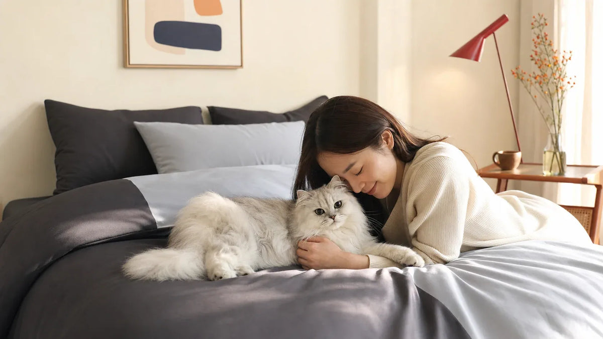 Long-haired cat resting on smooth CASUCA bedding in a shared bedroom