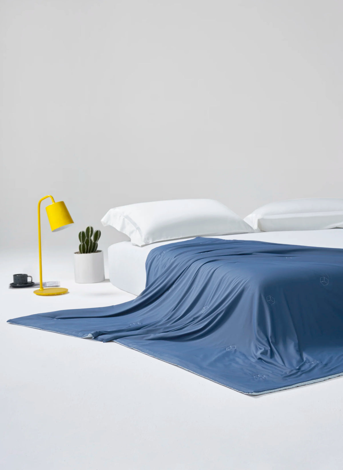Prussian blue CASUCA cooling comforter draped over a bed