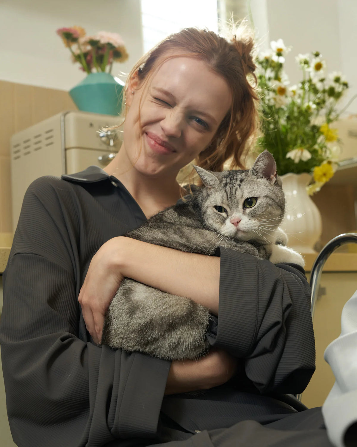 Woman in the grey CASUCA pet-hair-resistant loungewear set relaxing with a pet