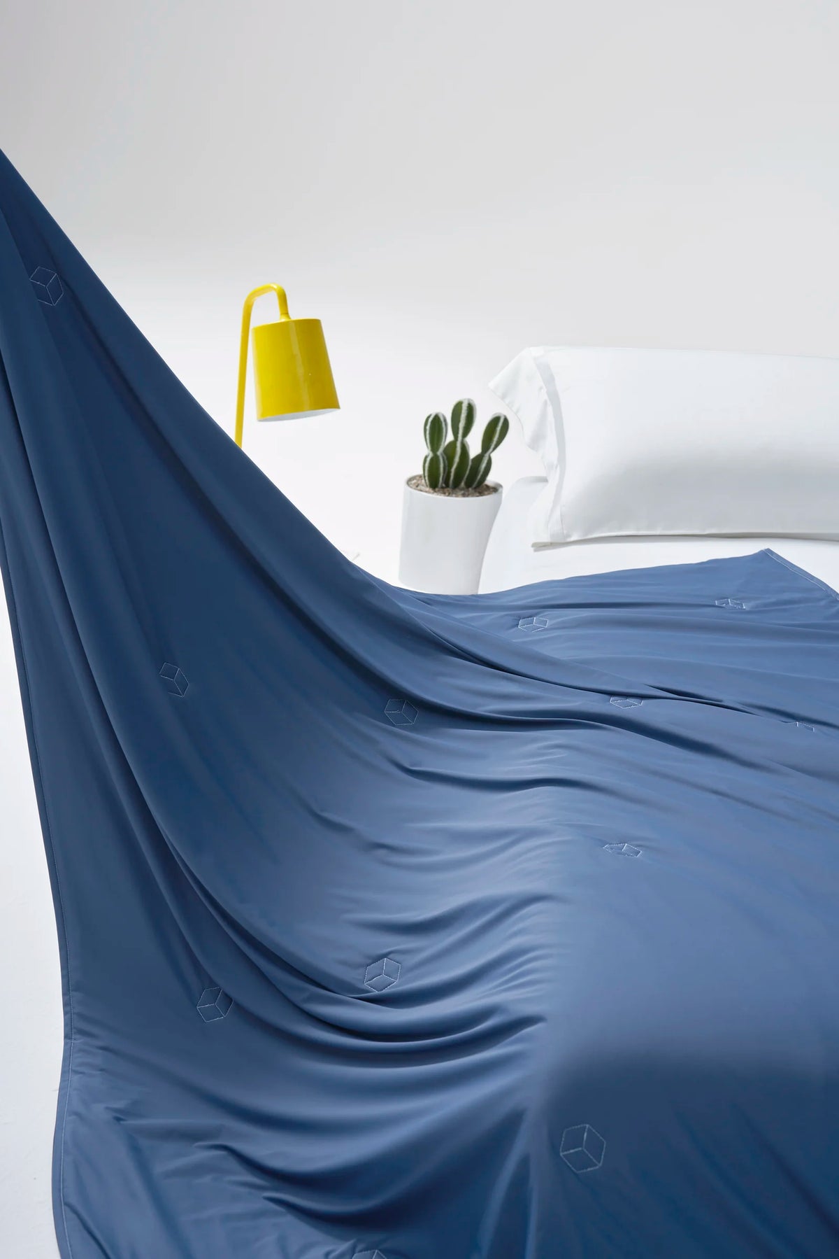 Prussian blue CASUCA cooling comforter arranged in a flowing drape