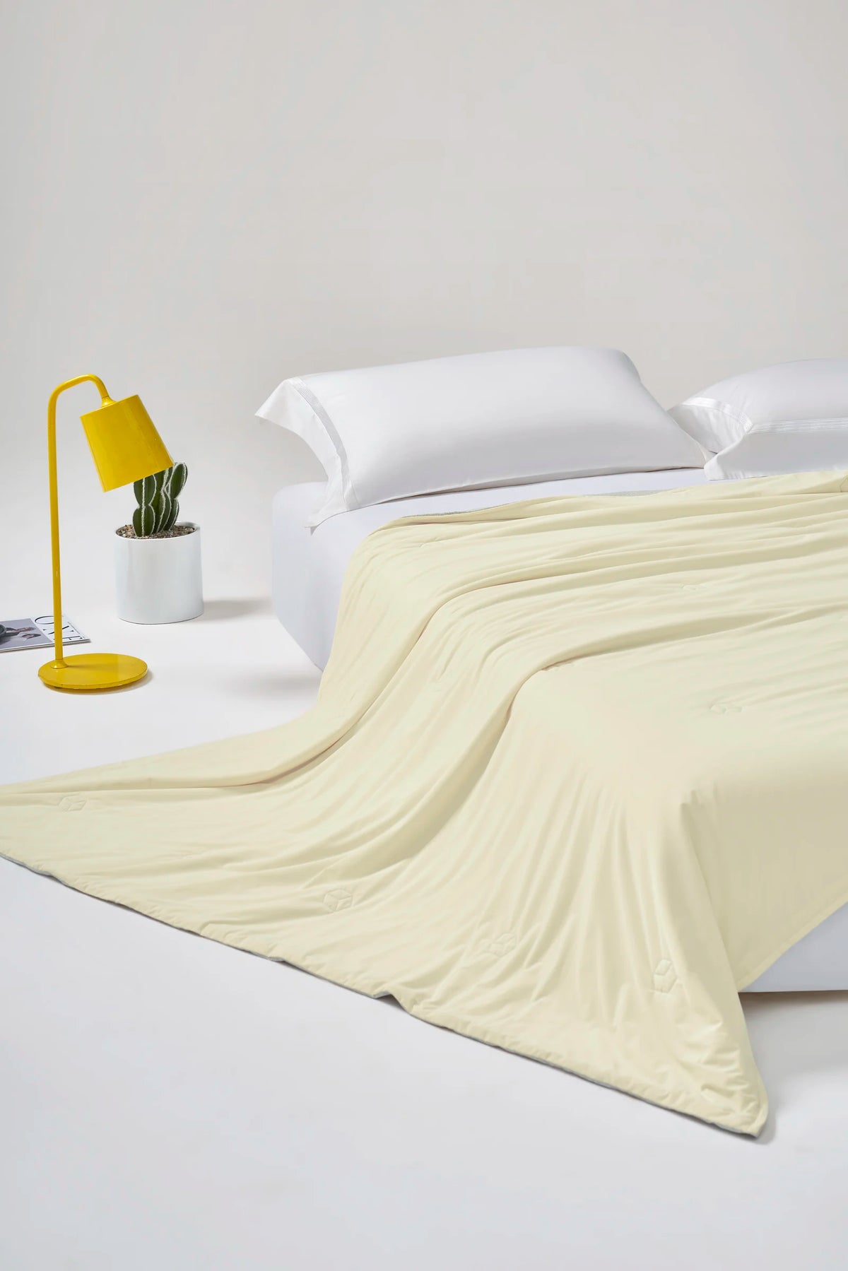 banana milk yellow CASUCA cooling comforter draped over a bed