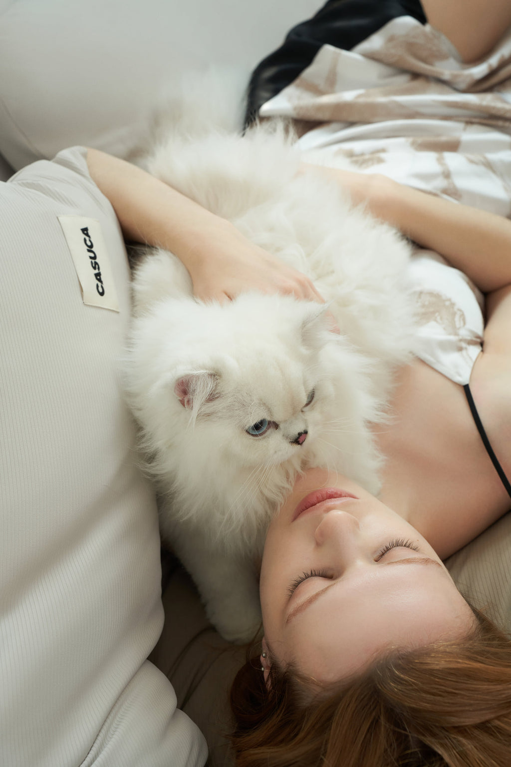 Woman sharing a close moment with a cat on the brown Peecatboo pet-hair-resistant four-piece bedding set